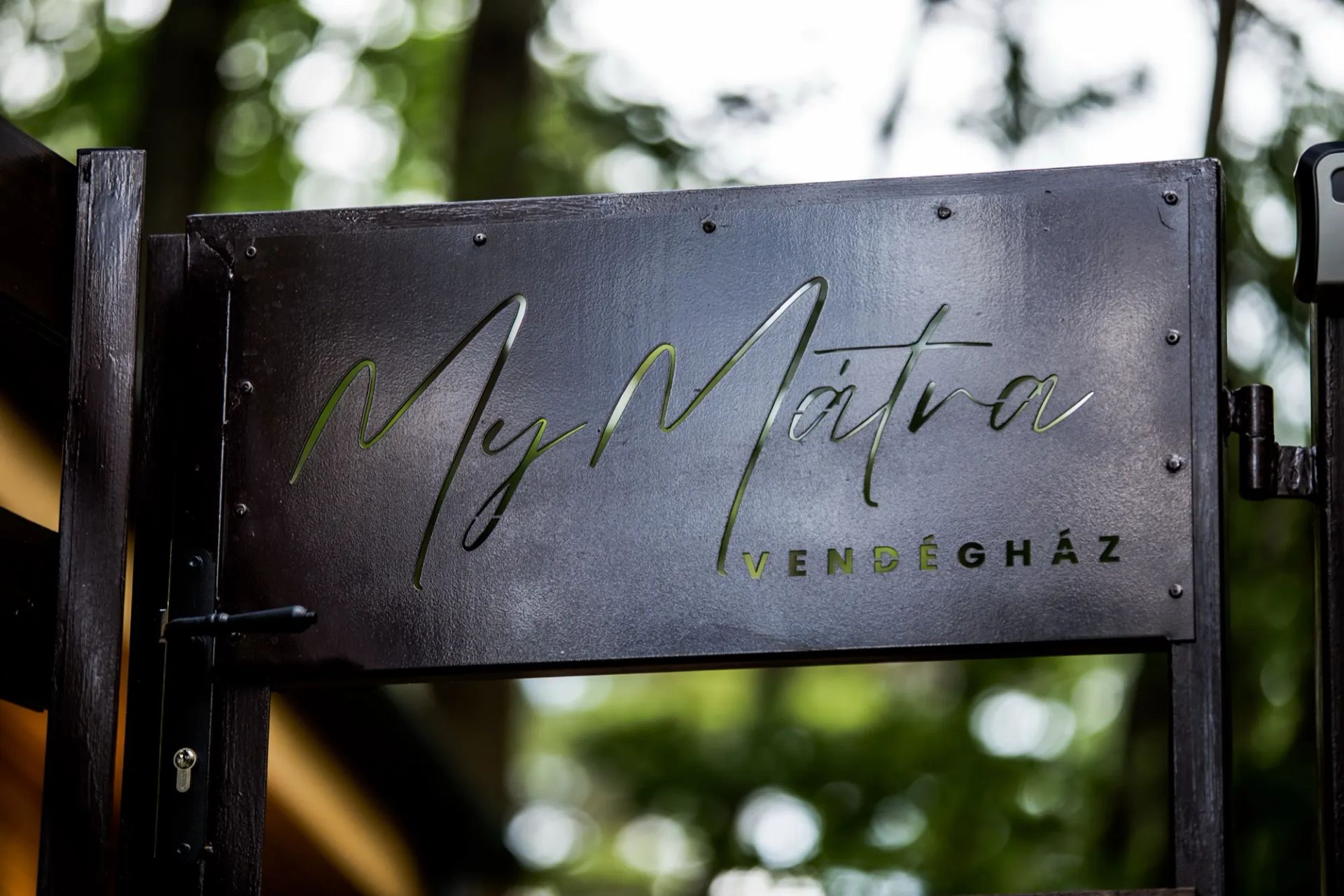MyMátra Vendégház feliratú fémtábla a fák között
