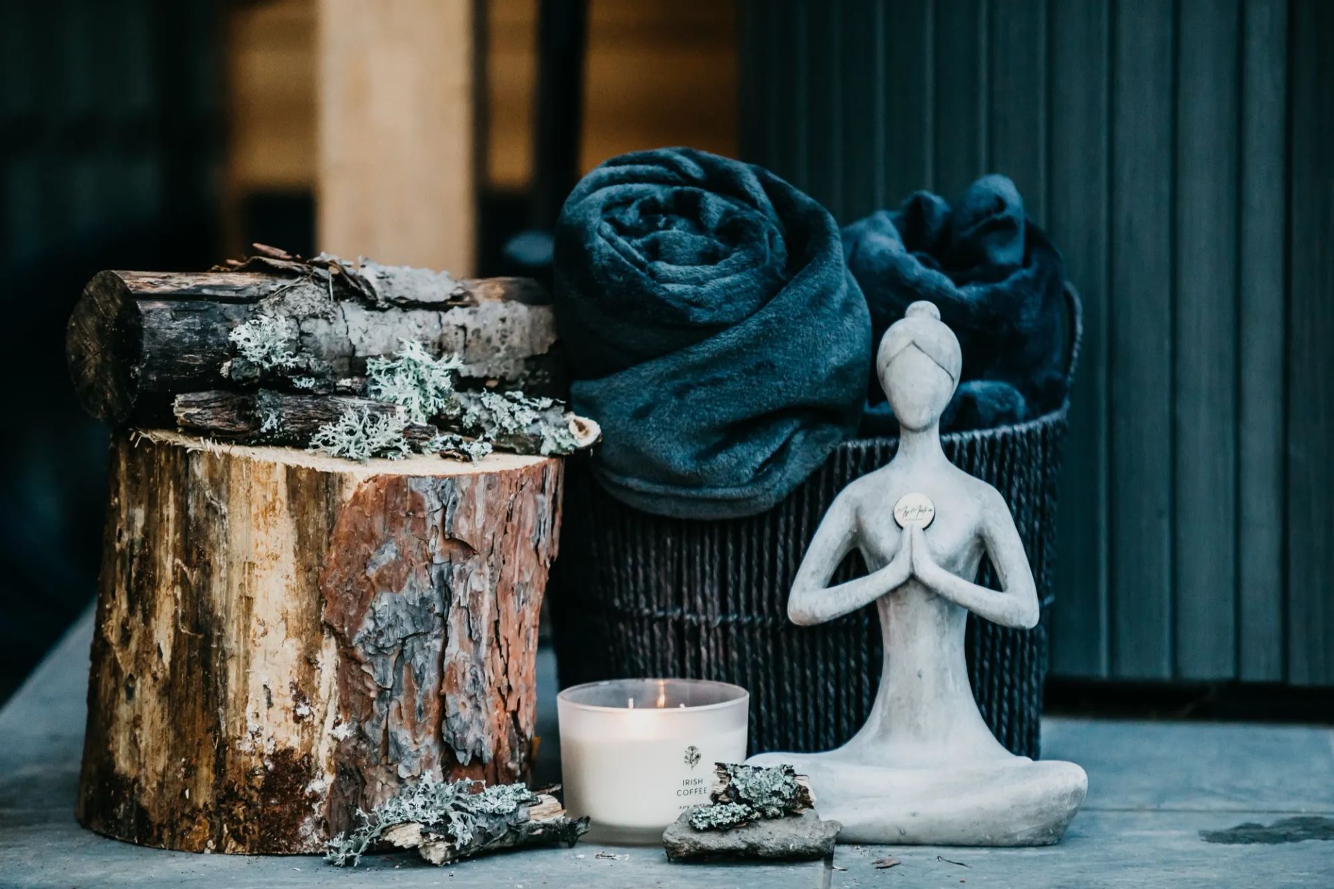 Meditáló figura, mécses és feltekert törölközők a jakuzzi mellett